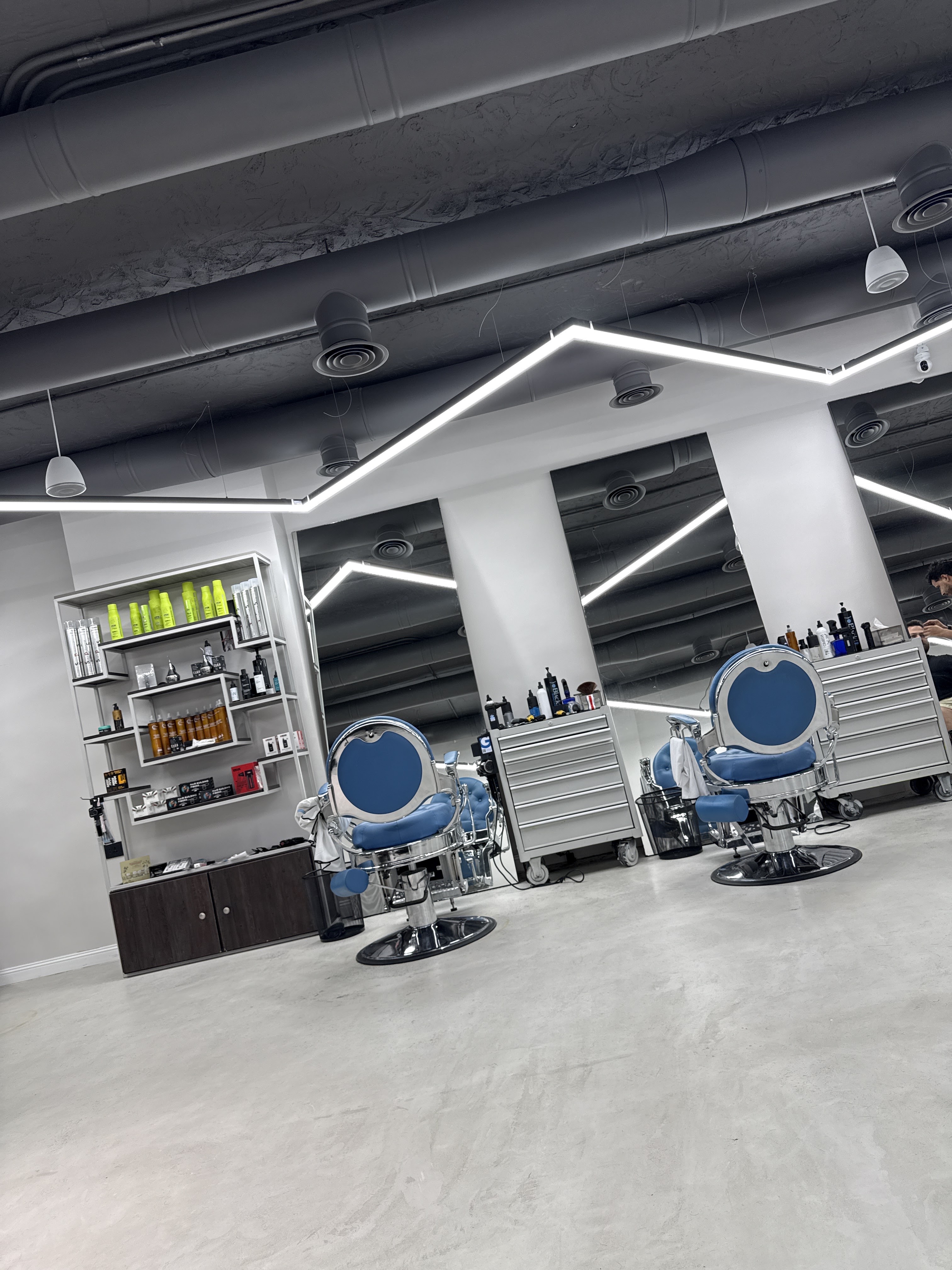 Row of chrome barber chairs with round blue backrests facing mirror stations
